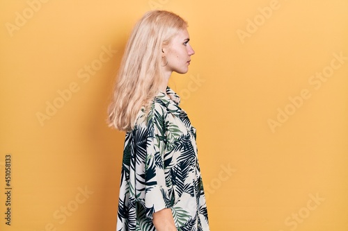 Beautiful caucasian woman with blond hair wearing tropical shirt looking to side, relax profile pose with natural face with confident smile.