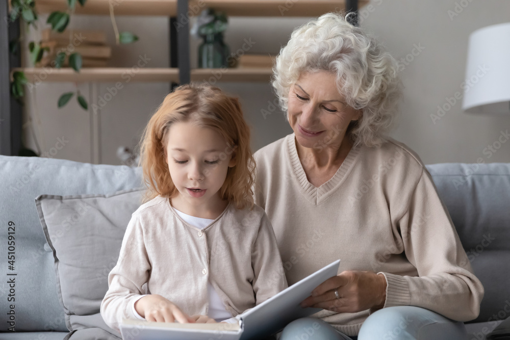 Loving old Caucasian 60s grandmother relax with little teen granddaughter read book together. Caring middle-aged grandma rest enjoy weekend hobby activity with literature with small grandchild. Loving old Caucasian 60s grandmother relax with little teen granddaughter read book together. Caring middle-aged grandma rest enjoy weekend hobby activity with literature with small grandchild.