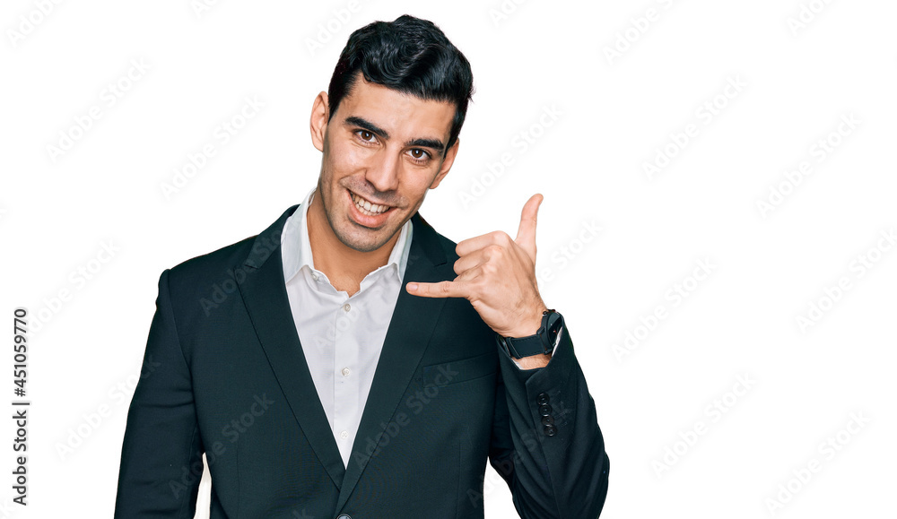 Handsome hispanic man wearing business clothes smiling doing phone gesture with hand and fingers like talking on the telephone. communicating concepts.