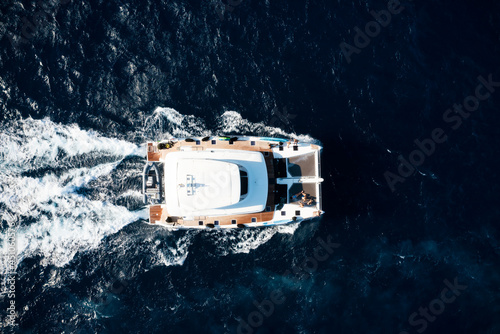 View from above, stunning aerial view of a catamaran sailing on a blue water. Costa Smeralda, Sardinia, Italy.