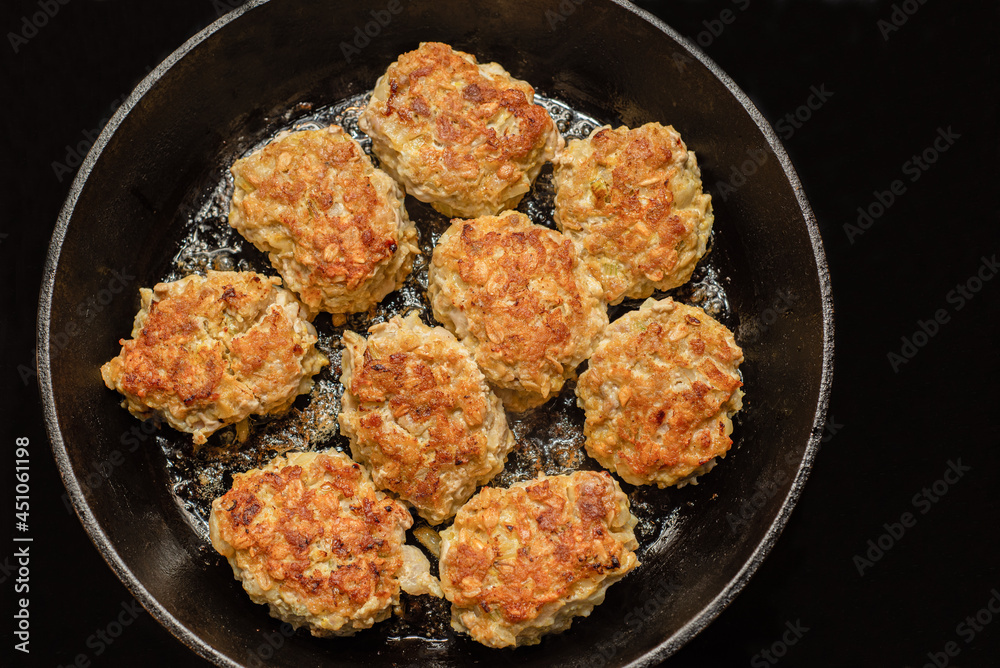 Homemade meatballs from minced meat cooked in a pan, top view, black background