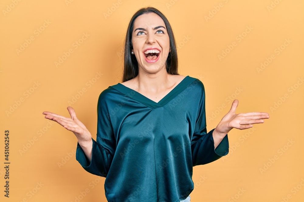 Beautiful woman with blue eyes wearing elegant shirt celebrating mad and crazy for success with arms raised and closed eyes screaming excited. winner concept Beautiful woman with blue eyes wearing elegant shirt celebrating mad and crazy for success with arms raised and closed eyes screaming excited. winner concept
