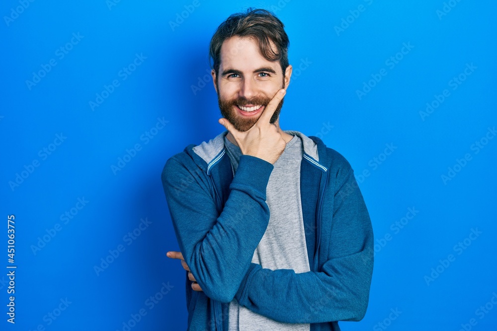 Caucasian man with beard wearing casual sweatshirt looking confident at the camera smiling with crossed arms and hand raised on chin. thinking positive. Caucasian man with beard wearing casual sweatshirt looking confident at the camera smiling with crossed arms and hand raised on chin. thinking positive.
