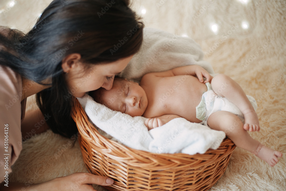 mom gently looks at her sleeping newborn baby.