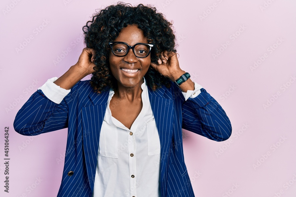 Young african american woman wearing business clothes and glasses smiling pulling ears with fingers, funny gesture. audition problem Young african american woman wearing business clothes and glasses smiling pulling ears with fingers, funny gesture. audition problem
