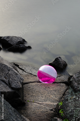 Beach ball trapped on rocks at the edge of the water in the fog photo