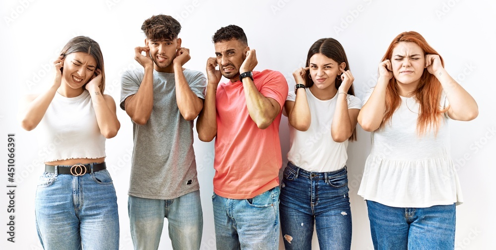 Group of young friends standing together over isolated background covering ears with fingers with annoyed expression for the noise of loud music. deaf concept. Group of young friends standing together over isolated background covering ears with fingers with annoyed expression for the noise of loud music. deaf concept.