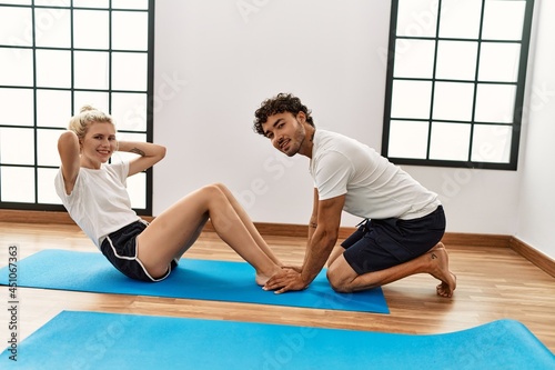 Young couple smiling happy training abs exercise at sport center.