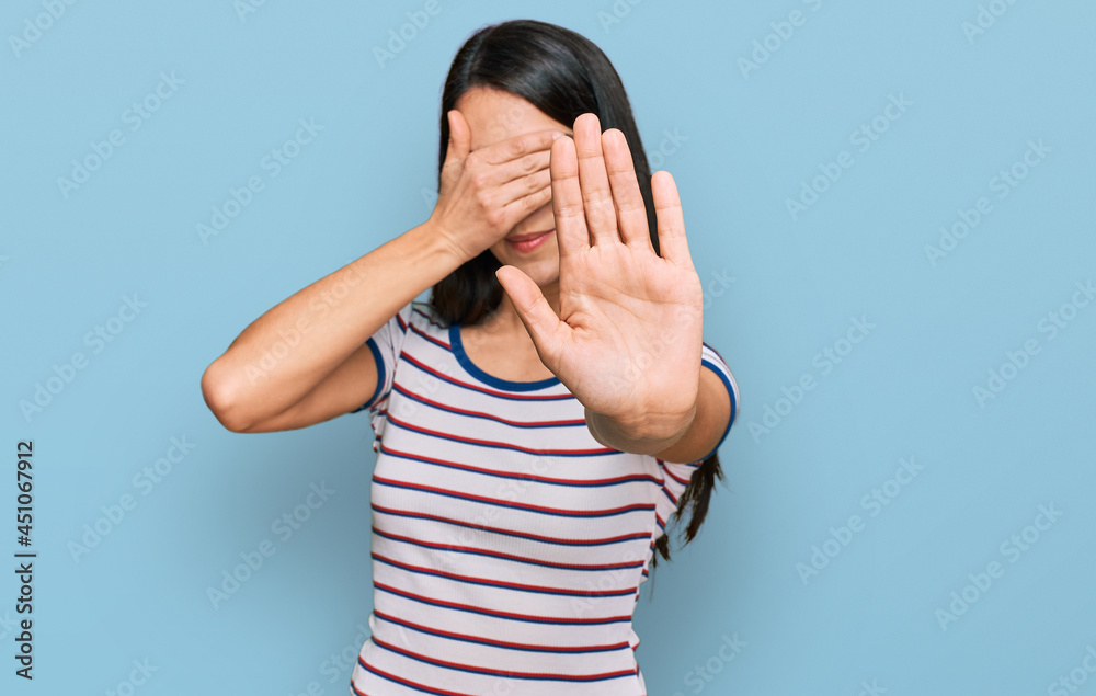 Young hispanic girl wearing casual striped t shirt covering eyes with hands and doing stop gesture with sad and fear expression. embarrassed and negative concept. Young hispanic girl wearing casual striped t shirt covering eyes with hands and doing stop gesture with sad and fear expression. embarrassed and negative concept.