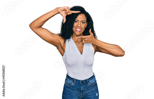 Middle age african american woman wearing casual style with sleeveless shirt smiling making frame with hands and fingers with happy face. creativity and photography concept.