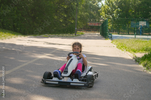 A child rides an electric go-kart in a city park. A young girl learns to drive an electric car. © Климов Максим