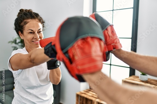 Middle age hispanic couple smiling happy training boxing at home. © Krakenimages.com