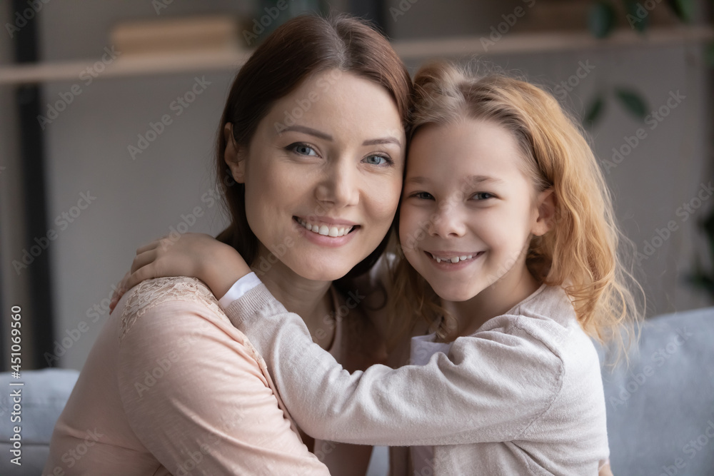 Close up portrait of smiling young Caucasian mom and little daughter hug cuddle show love and care. Happy mother embrace small teen girl child demonstrate family unity bonding. Motherhood concept. Close up portrait of smiling young Caucasian mom and little daughter hug cuddle show love and care. Happy mother embrace small teen girl child demonstrate family unity bonding. Motherhood concept.