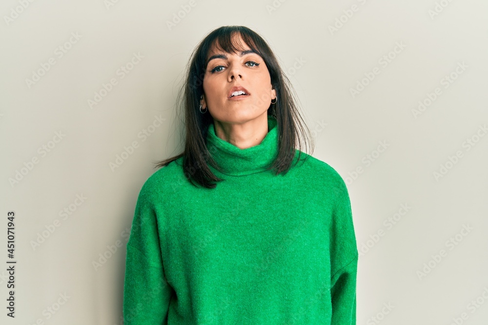 Young hispanic woman wearing casual winter sweater with serious expression on face. simple and natural looking at the camera. Young hispanic woman wearing casual winter sweater with serious expression on face. simple and natural looking at the camera.