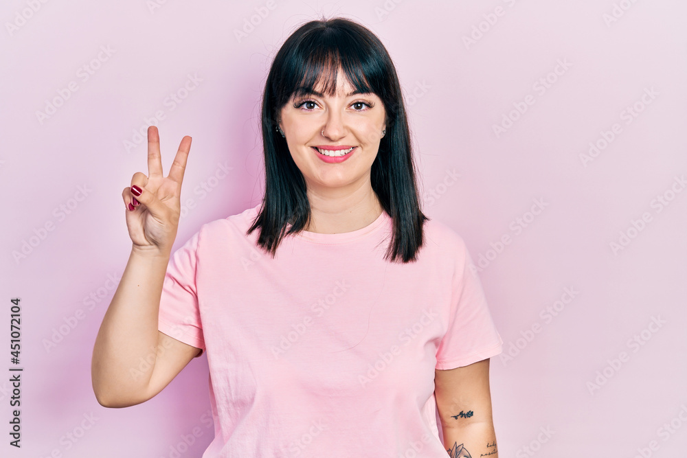 Young hispanic woman wearing casual clothes showing and pointing up with fingers number two while smiling confident and happy. Young hispanic woman wearing casual clothes showing and pointing up with fingers number two while smiling confident and happy.