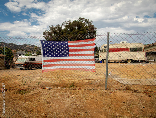 American flag attached to a chain link fence in a rural impoverished area photo