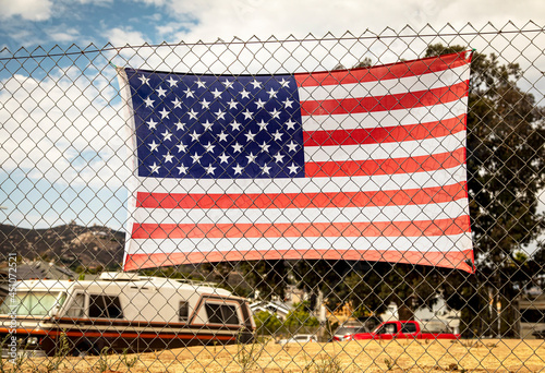 American flag attached to a chain link fence in a rural impoverished area