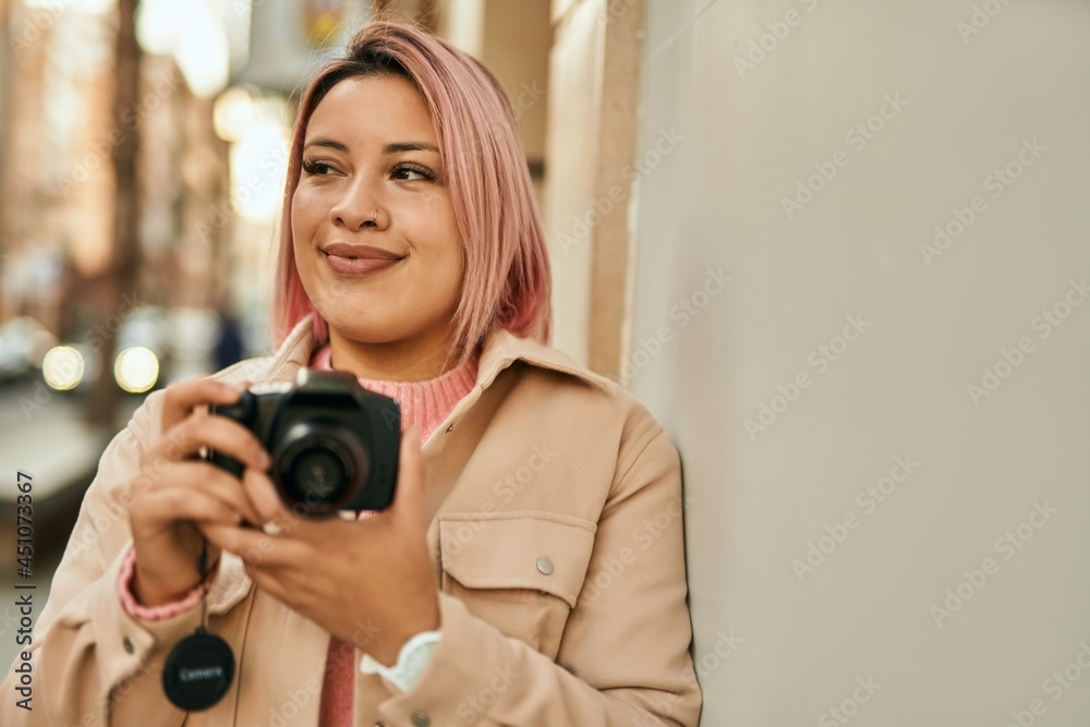 Young hispanic girl smiling happy using reflex camera at the city.