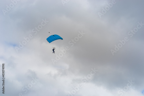 Skydiving as an exciting but extreme sport. People descend on blue parachutes