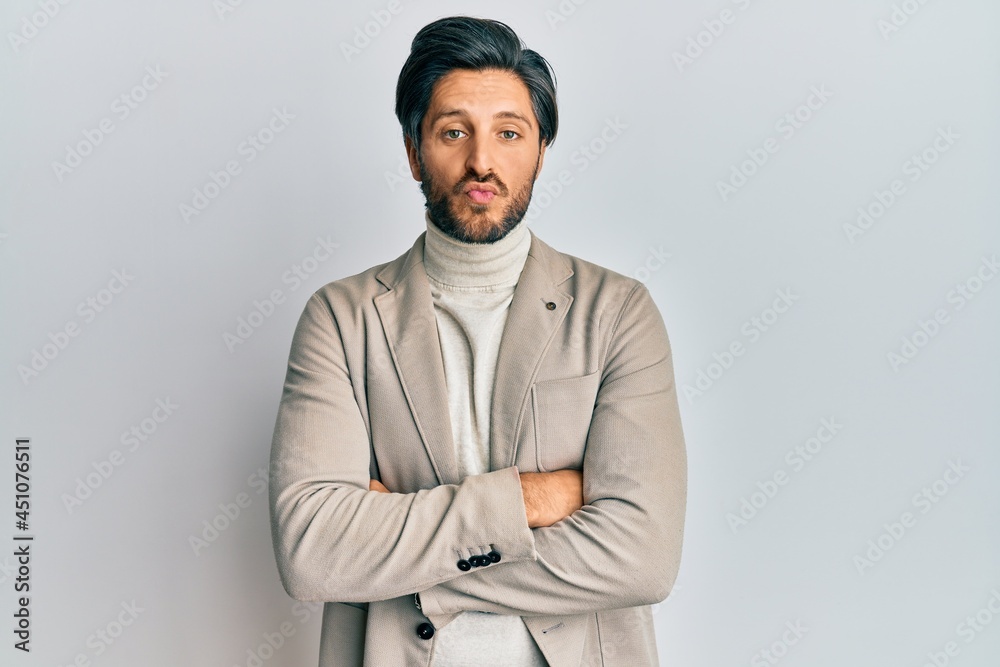 Obraz premium Young hispanic man with arms crossed gesture looking at the camera blowing a kiss being lovely and sexy. love expression.