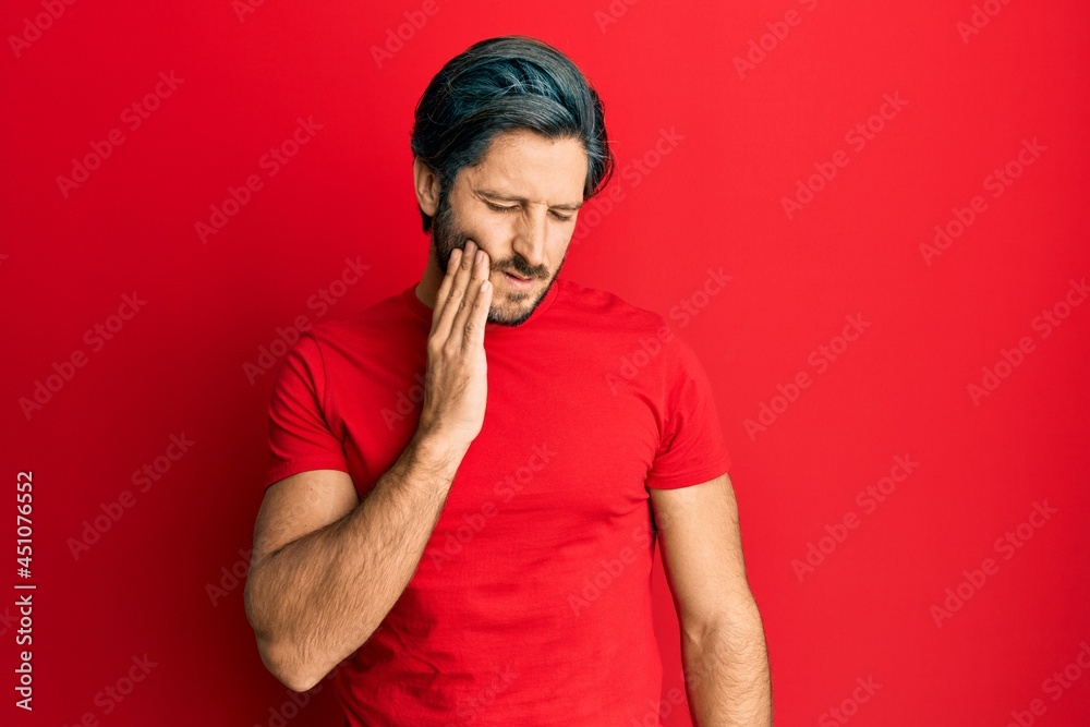 Young hispanic man wearing casual red t shirt touching mouth with hand with painful expression because of toothache or dental illness on teeth. dentist Young hispanic man wearing casual red t shirt touching mouth with hand with painful expression because of toothache or dental illness on teeth. dentist