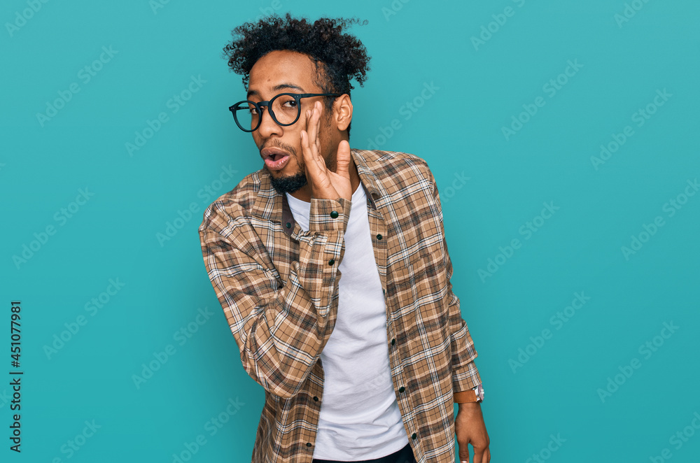 Young african american man with beard wearing casual clothes and glasses hand on mouth telling secret rumor, whispering malicious talk conversation Young african american man with beard wearing casual clothes and glasses hand on mouth telling secret rumor, whispering malicious talk conversation