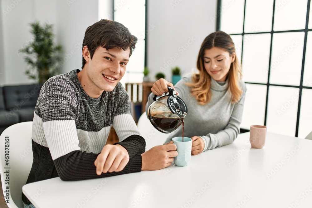 Young caucasian couple having breakfast pouring coffee on cup at home. Young caucasian couple having breakfast pouring coffee on cup at home.