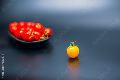 Fotografia Discrimination Concept, Focused raw excluded tomato at foreground and defocused group of red tomatoes at background