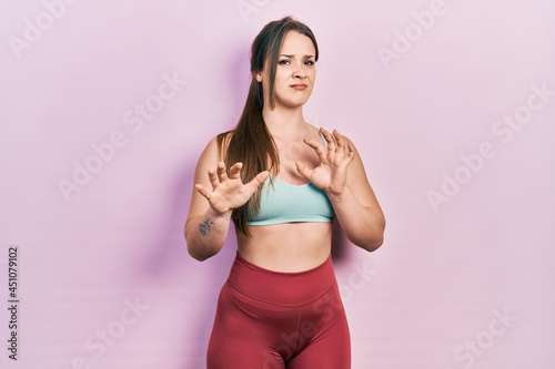 Young hispanic girl wearing sportswear disgusted expression  displeased and fearful doing disgust face because aversion reaction. with hands raised