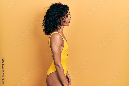 Young latin girl wearing swimsuit looking to side, relax profile pose with natural face with confident smile.