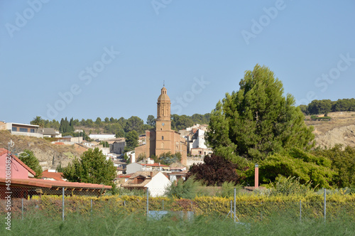 La iglesia de Andosilla, Navarra desde el campo. Paisaje amenizado por una iglesia y casas adyacentes. Cielo despejado y vejetacion verde. Foto equilibrada. photo