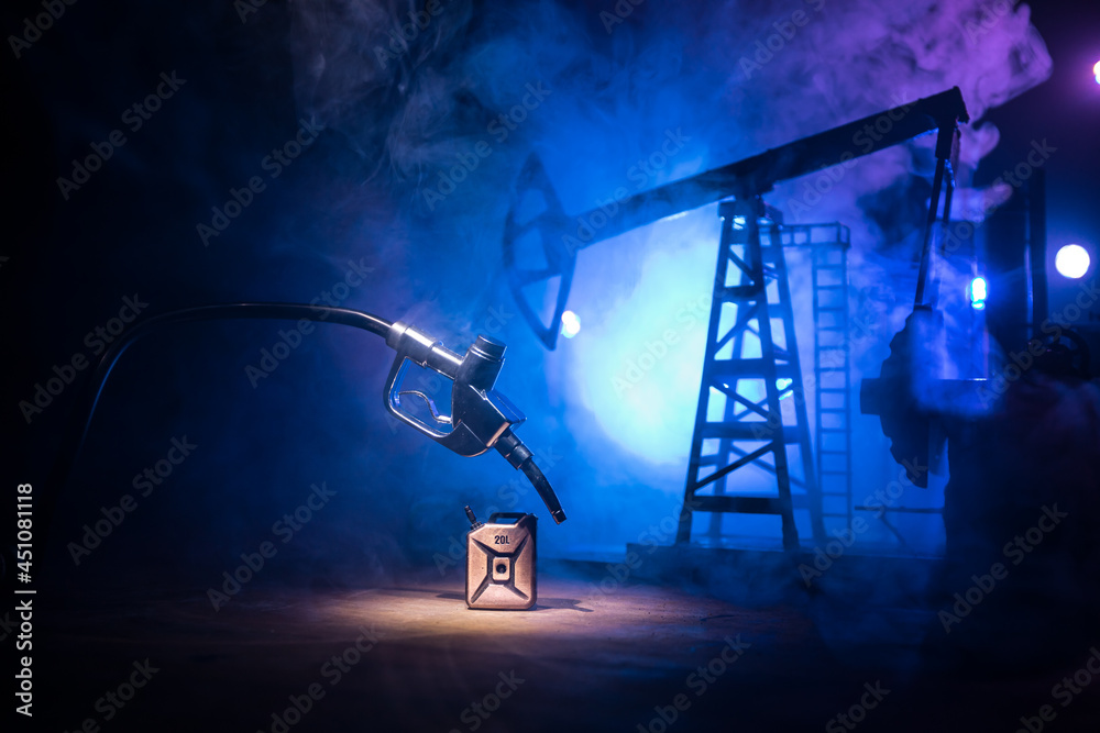 Creative concept. Silhouette of gasoline pistol miniature on dark toned foggy background. Close up. Industrial decorated elements on background.