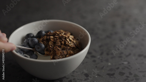 Man eat granola with yogurt and blueberries in white bowl