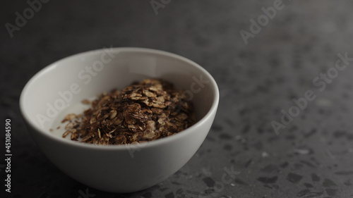 Pour granola over yogurt in white bowl