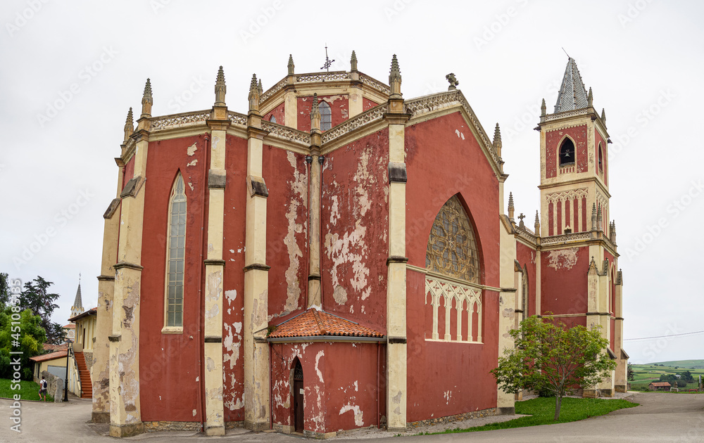 Vistas de la fachada roja y ocre de estilo neogótico de la Iglesia de San Pedro Advíncula, en Cobreces, Cantabria, verano de 2020