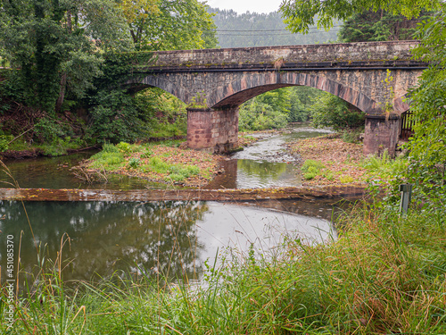 Vistas del puente de piedra reflejado en el agua el río en el área recreativa Las Cuevas en Cantabria, España, verano de 2020.