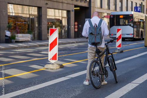 Adult man with backpack stand over bicycle on bicycle lane in downtown Düsseldorf, Germany. photo