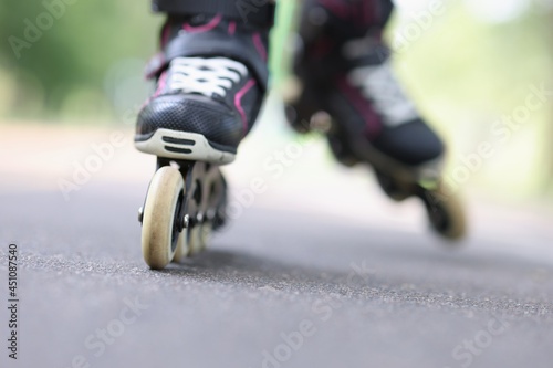 Child riding black rollerblades on road closeup photo