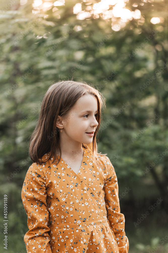 Vertical portrait of a beautiful little girl in the park in the summer. Looking away Vertical portrait of a beautiful little girl in the park in the summer. Looking away