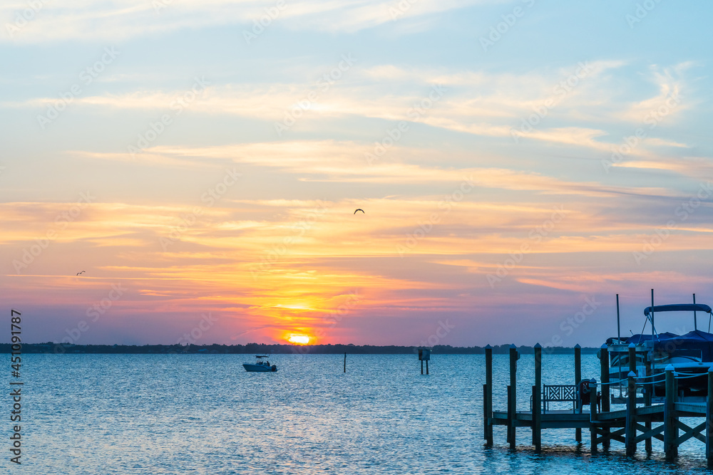 Orange sunset on Indian River, Vero Beach, Florida. Boats and wooden piers on the horizon