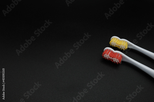orange and yellow toothbrushes on black background