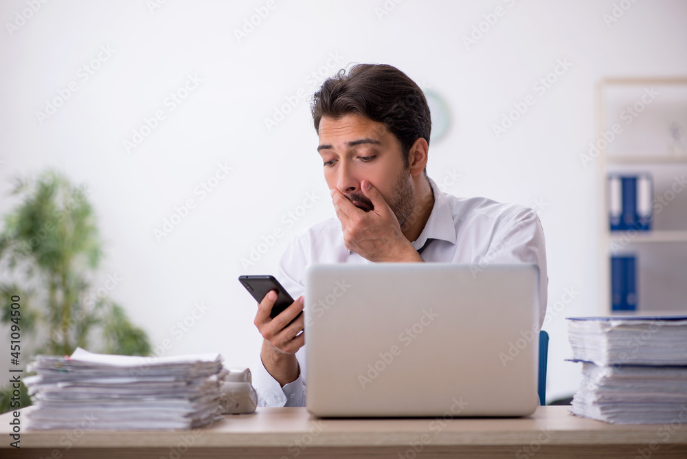 Young male employee unhappy with excessive work in the office