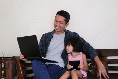 A father showing something in a laptop to his daughter photo