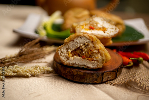 Tahu isi  Indonesian traditional food  fried tofu filled with vegetables  served on wood plate on golden tablecloth