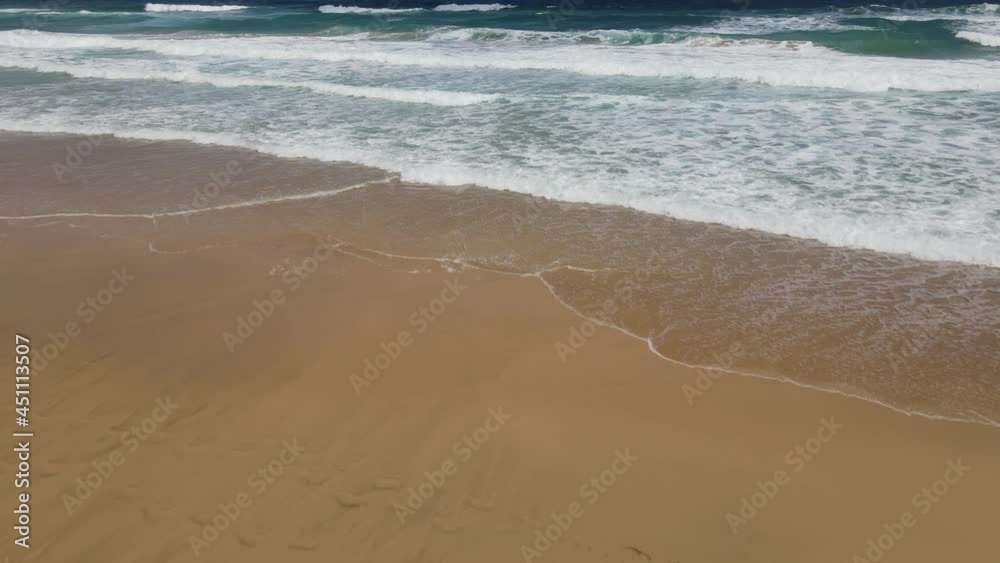 Low altitude drone backward movement over a deserted sandy paradise beach. Sea waves breaking on sandy coastline. Low altitude drone backward movement over a deserted sandy paradise beach. Sea waves breaking on sandy coastline.