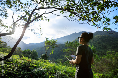 Remotel controlling a  flying drone in tropical forest photo