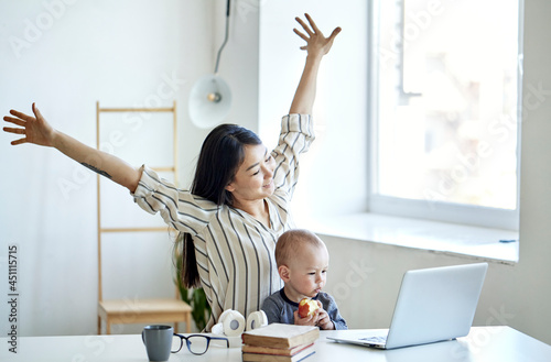Young mother freelancer with her child working at home office using laptop
