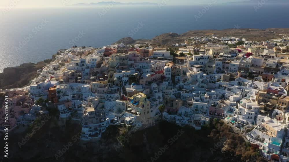 Oia with white cave houses and villas top down view from drone rising during sunset in Santorini, Greece. Oia with white cave houses and villas top down view from drone rising during sunset in Santorini, Greece.