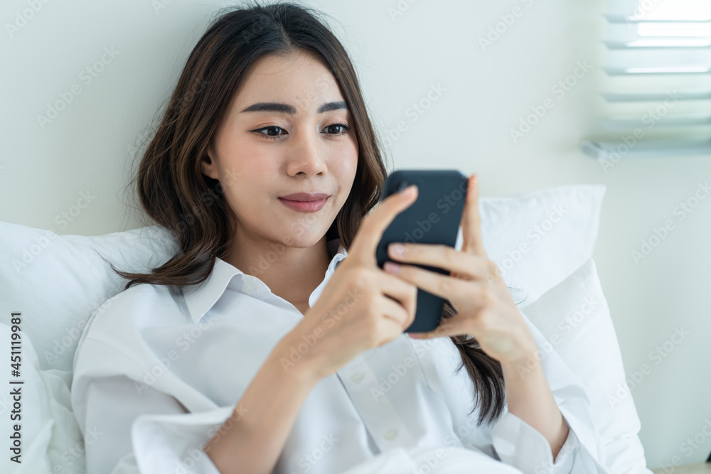 Asian attractive woman use mobile phone chat on bed at home in morning. Asian attractive woman use mobile phone chat on bed at home in morning.