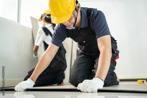 Asian Craftsman worker people installs laminate board on floor at home